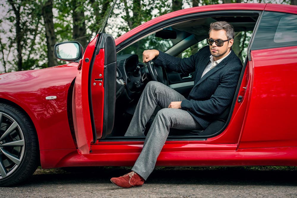 middle-aged man stepping out of red sports car