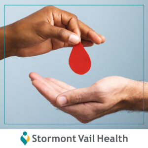 One hand placing a paper shaped blood drop into another hand.