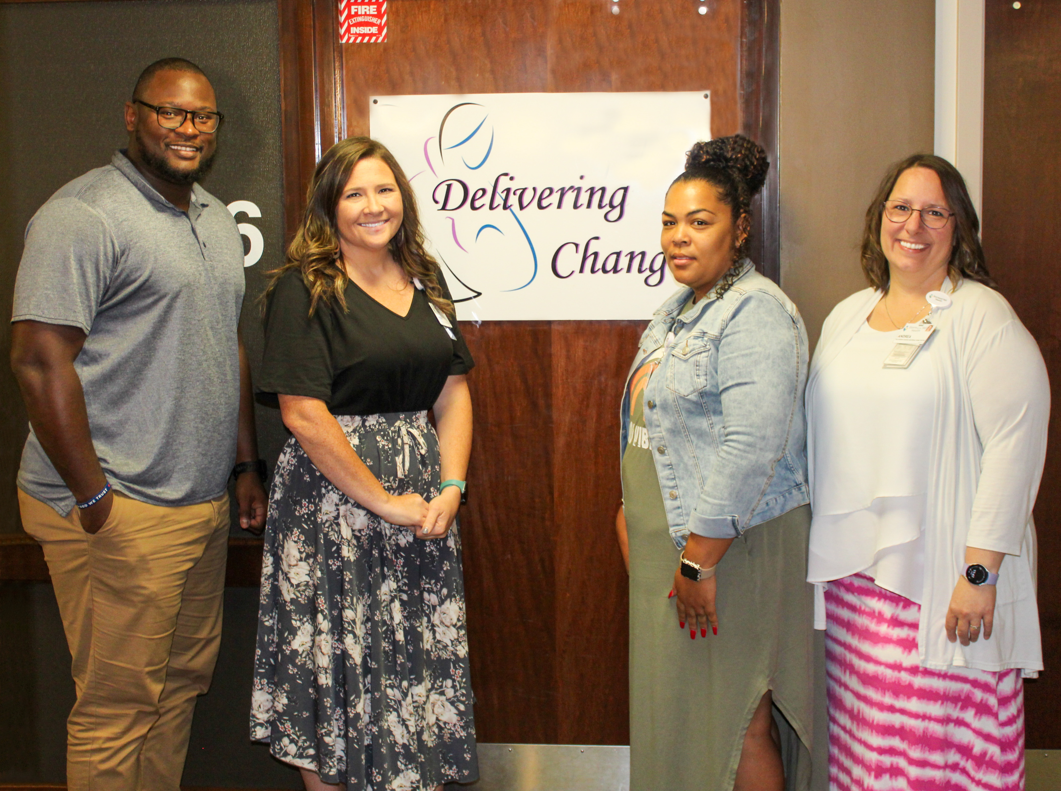 A group of health care working standing in front of a Delivering Change sign at Stormont Vail Health Manhattan