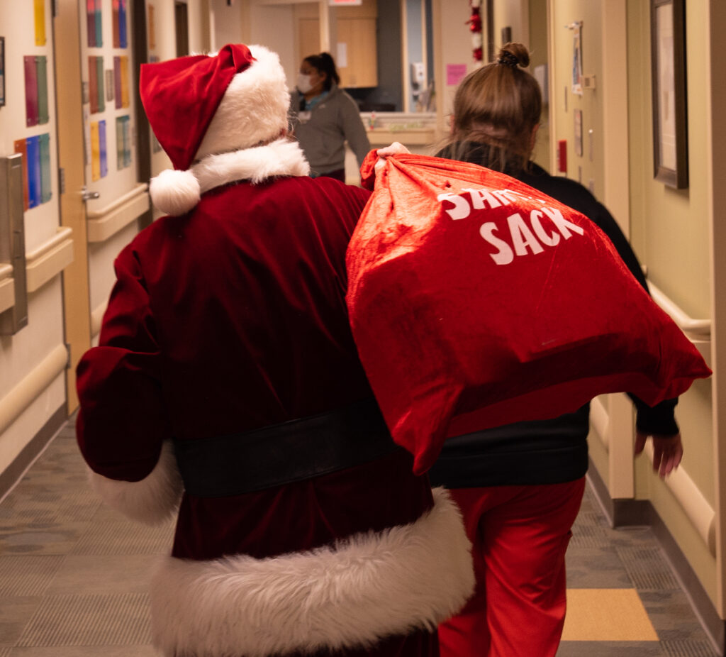 Santa walking down the hospital hallway to go visit children