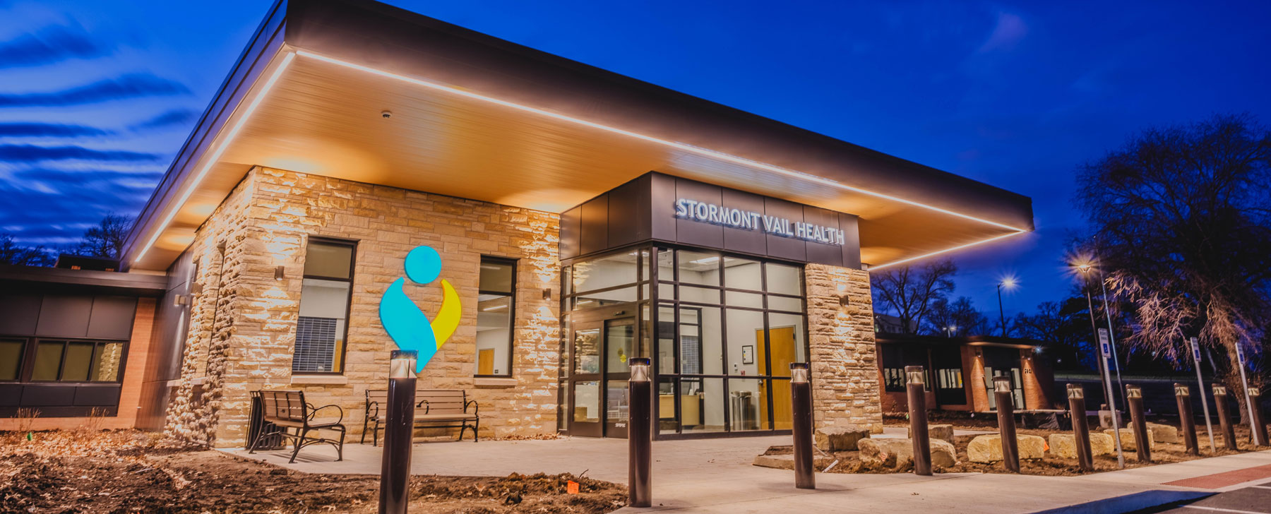 Modern Stormont Vail Health building exterior at dusk with illuminated signage, stone façade, and glass entrance in Topeka, Kansas.