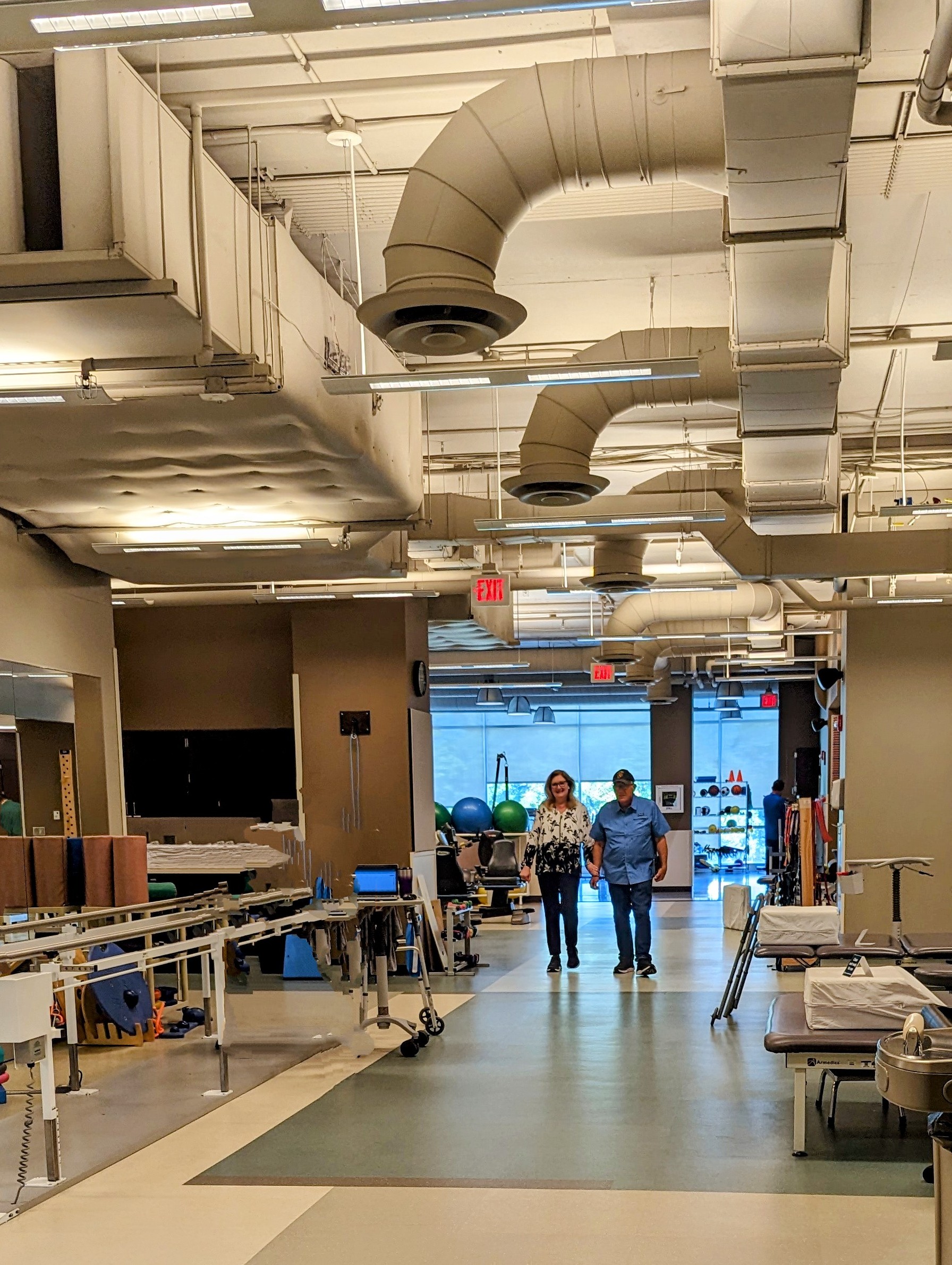 two people walking through a physical therapy area