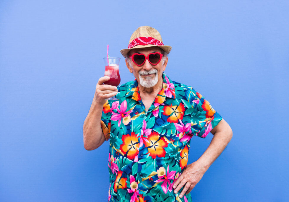 Funny and extravagant senior man posing on colored background - Youthful old man in the sixties having fun and partying