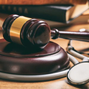 Law gavel and a stethoscope on a wooden desk, dark background